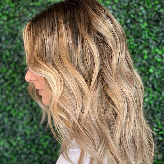 Side profile of woman with long, beachy blonde hair and teasy lights, created using Wella Professionals.