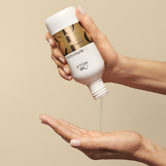 Oil Reflections Luminous Reveal Shampoo is poured into a model’s hand.