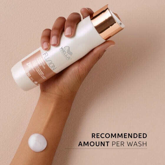 Hand holds up a bottle of Fusion Intense Repair Shampoo.
