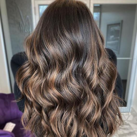 Back of woman’s head with long, dark brown hair and toffee highlights.