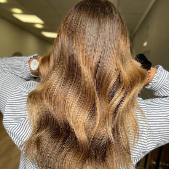 Back of woman’s head with long, light brown hair and toffee blonde highlights.