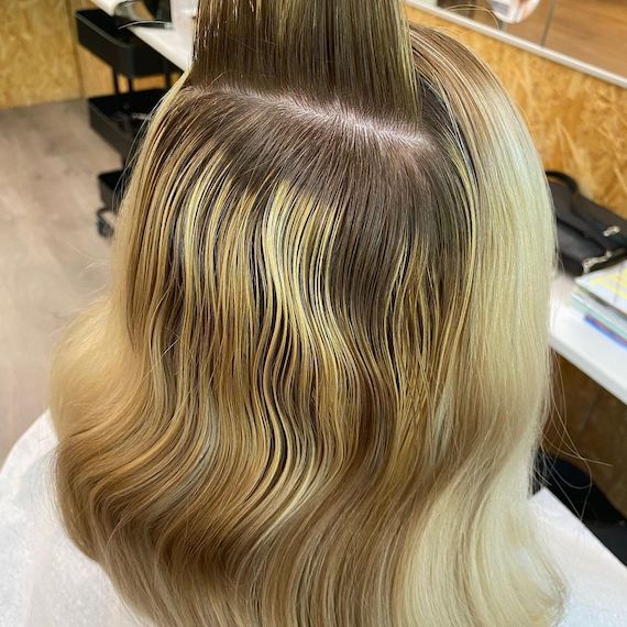 Back of woman’s head with mid-length, brassy hair and grown-out roots.