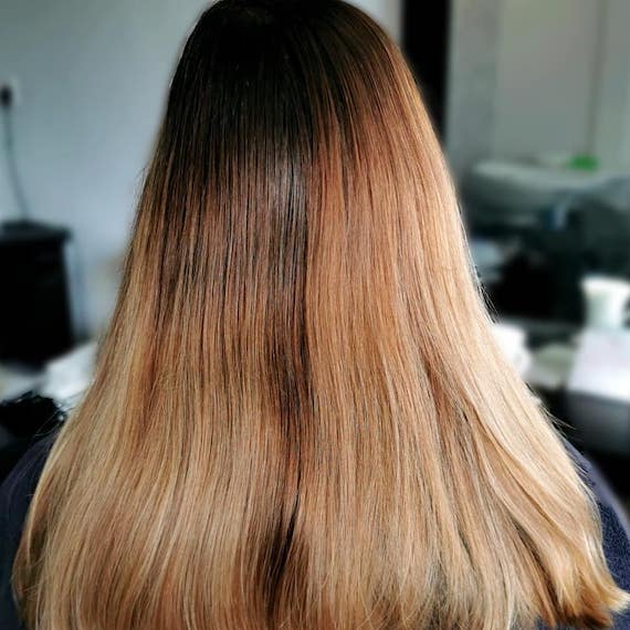 Back of woman’s head with long, brassy hair and grown-out roots.