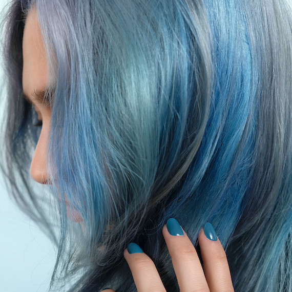 model touches her light blue hair. They have blue nails to match