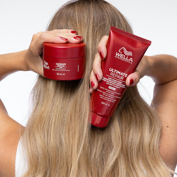 Back of model’s head with long, blonde hair. The model is holding up the ULTIMATE REPAIR Mask and ULTIMATE REPAIR Conditioner. 