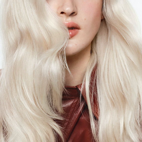 Close-up of model’s long, loosely tousled, platinum blonde hair.