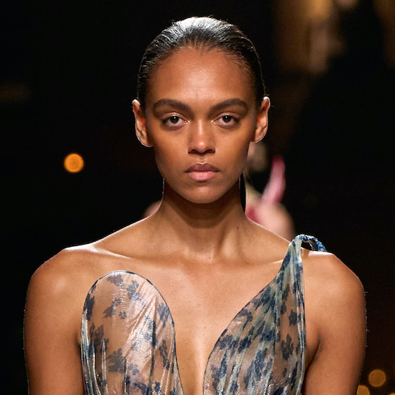 A model on the Victoria Beckham SS25 runway with dark hair slicked back.