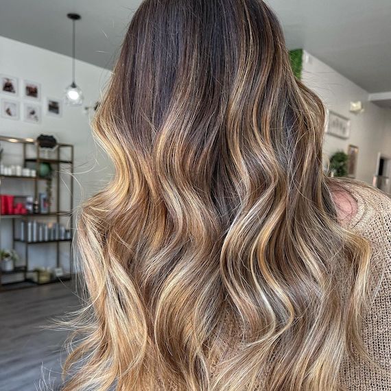 A person faces away from the camera showing their wavy walnut blonde hair