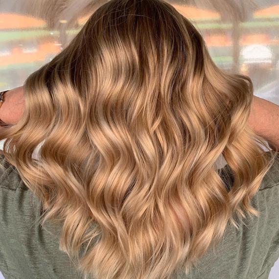 Photo showing the back of a woman’s head with long, wavy, balayage hair. Created using Wella Professionals. 