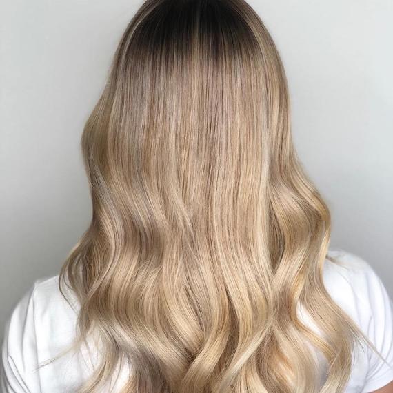 Photo showing the back of a woman’s head with long, loosely-curled, creamy blonde hair. Created using Wella Professionals. 