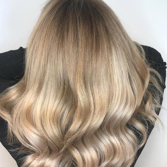 Photo showing the back of a woman’s head with long, loosely-curled, beige blonde hair. Created using Wella Professionals. 