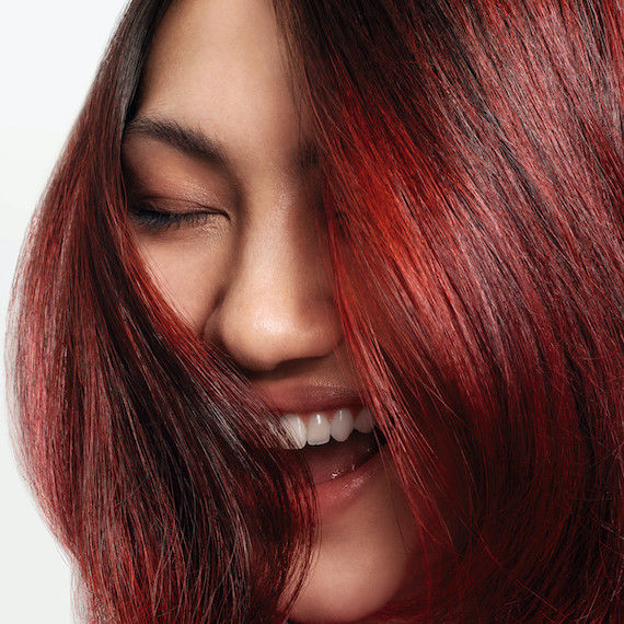 Close-up of model with dark brown and red, glossy hair.