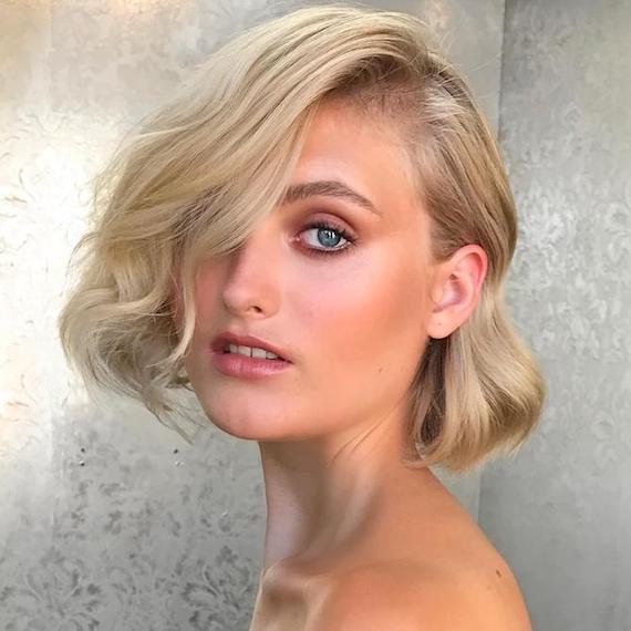 Photo of woman with short wedding hairstyle. Hair is styled in a wavy bob with a deep side parting, created using Wella Professionals