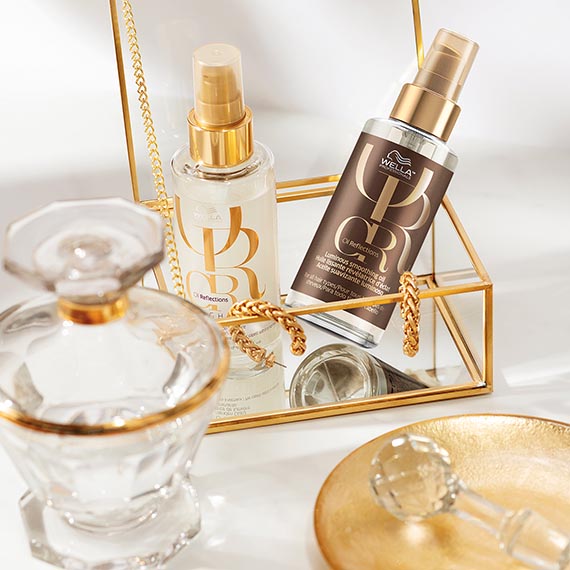 Wella Professionals Oil Reflections Smoothing Oils arranged in a gold box surrounded by glass ornaments 