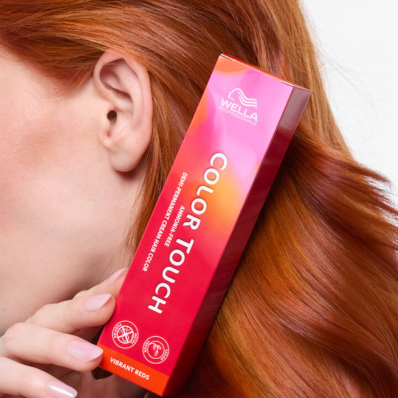 Model with straight, copper hair holding up a box of Color Touch.