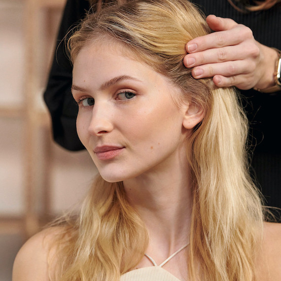 Model mit langem, gewelltem, blondem Haar bei einer Haarberatung mit ihrem Stylisten.