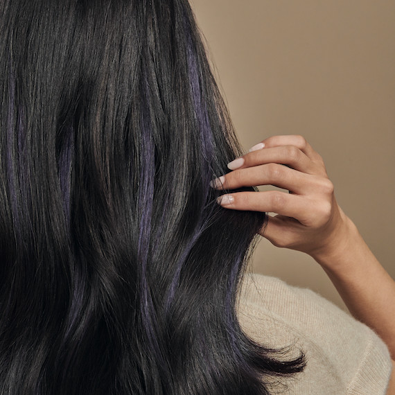 Back of model’s head with long, dark, straight hair fanning behind them.