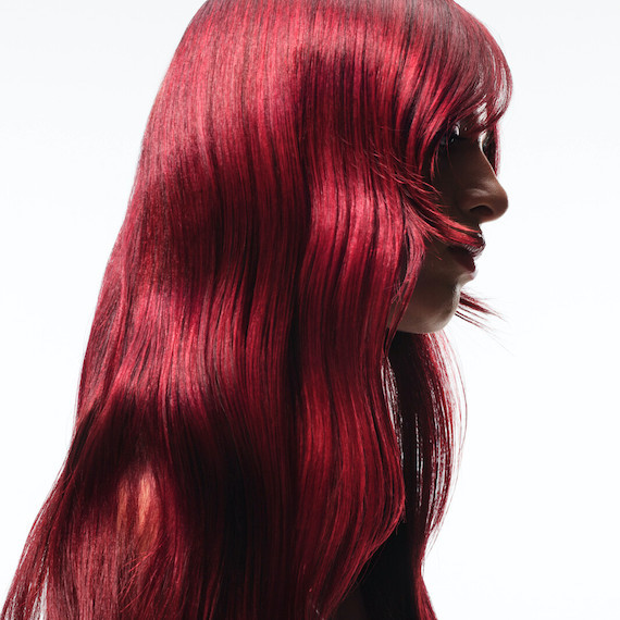 Side profile of model with long, wavy, cherry red hair.