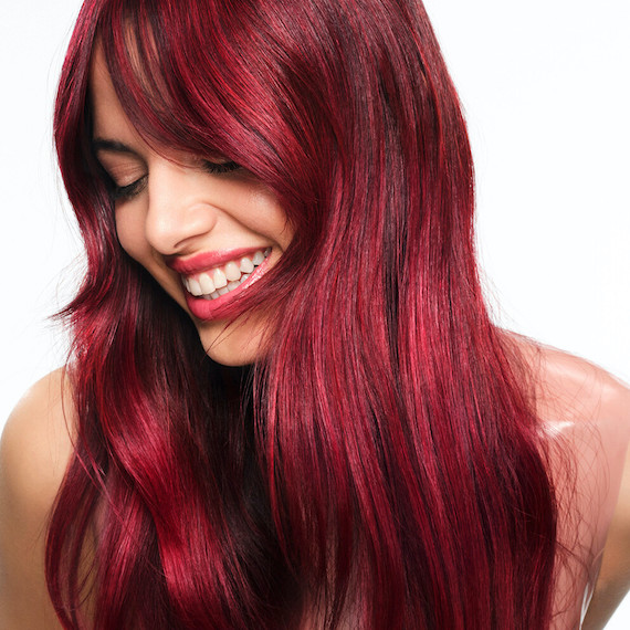 Model with long, loosely wavy, ultra-glossy, cherry red hair.