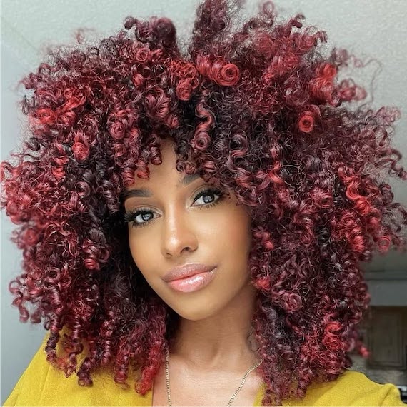 Model with black, curly hair featuring cherry red highlights.