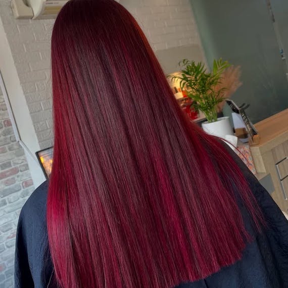 Back of model’s head with long, straight, dark cherry red hair.