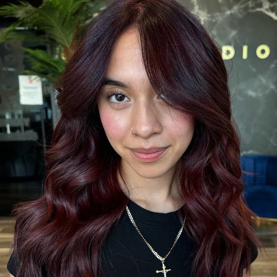 Model with long, loosely curled, cherry burgundy hair.