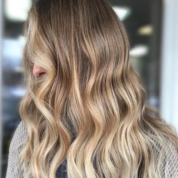 Seitenprofilaufnahme einer Frau mit langer, gewellter, Balayage, kreiert mit Wella Professionals