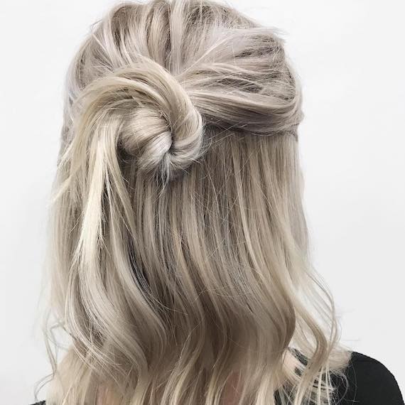 Back of a woman’s head with hair styled in an ash blonde, half-up bun, created using Wella Professionals