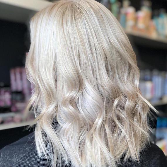Icy ash blonde hair styled in loose curls, created using Wella Professionals
