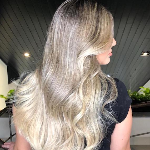 Side profile shot of woman with long, wavy, ash blonde hair, created using Wella Professionals