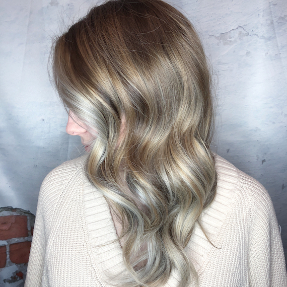 Side profile shot of woman with loosely-curled, ash blonde hair, created using Wella Professionals