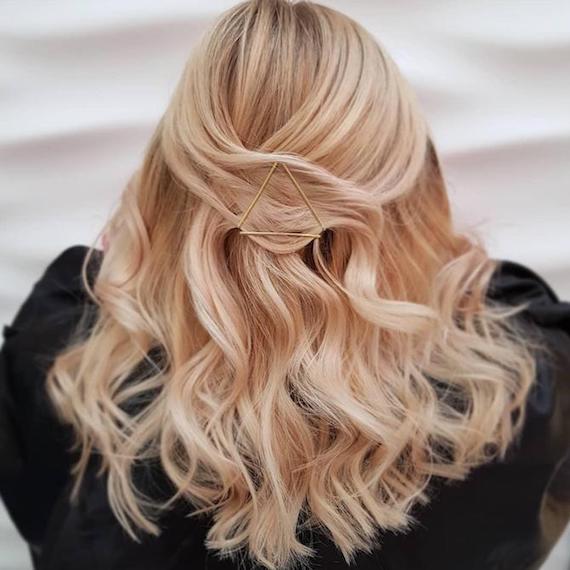 Back of woman’s head with long, wavy hair decorated using bobby pins