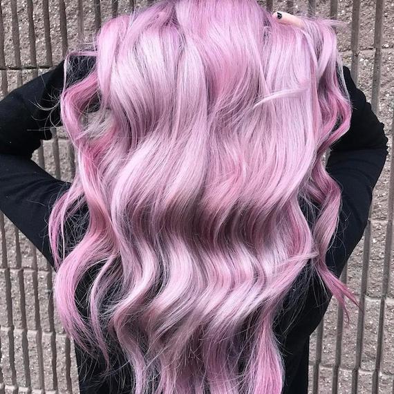 Photo showing the back of a woman’s head as she swishes her long, wavy, metallic pink hair, created using Wella Professionals