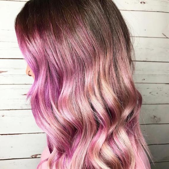 Side-on photo of model with long, wavy, bright pink hair, created using Wella Professionals