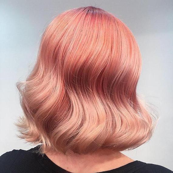 Back of woman’s head showing wavy, pinky-peach hair color, created using Wella Professionals