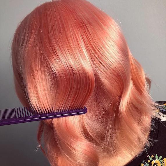 Head with a comb running through wavy, peach hair color, created using Wella Professionals