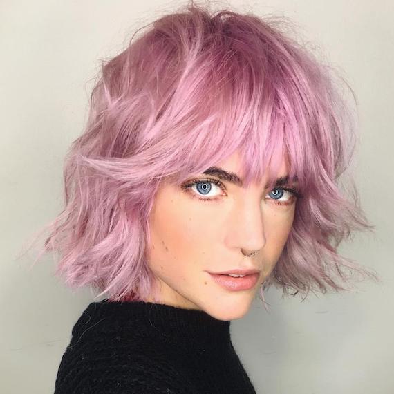 Front-on photo of woman with tousled bob and fringe in a metallic pink shade, created using Wella Professionals