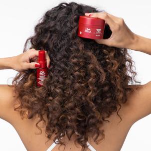Model with curly hair holds up ULTIMATE REPAIR Miracle Hair Rescue and Mask.