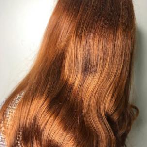 Photo of the back of a woman’s head with mid-length, loose waves and pumpkin spice hair color, created using Wella Professionals.