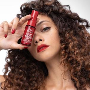 Model with dark brown, curly hair holds ULTIMATE REPAIR Miracle Hair Rescue in front of their face.