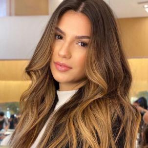 Model with long, brown caramel ombre hair looks at the camera 