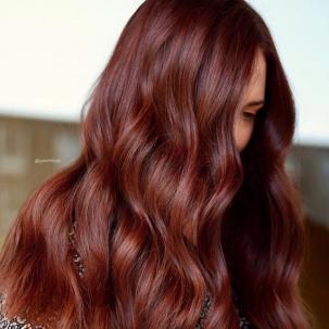 Side profile of woman with long, wavy, mahogany red brown hair, created using Wel-la Professionals.