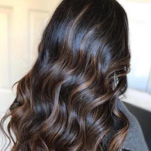 Foto vom Hinterkopf einer Frau mit langem, schwarzem Haar und brauner Balayage, kreiert mit Wella Professionals.