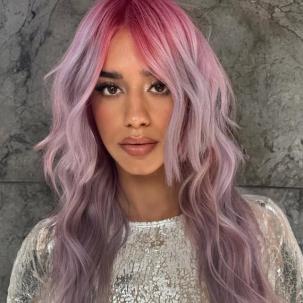 Model with pink to purple ombre hair styled in loose waves.