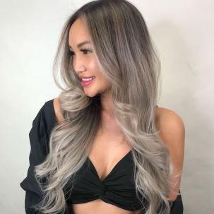 Model with long, silvery, ash blonde ombre hair glances to the side.