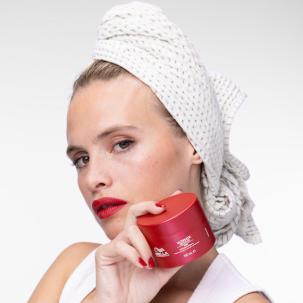 Model with clean, damp hair wrapped in a towel holds up ULTIMATE REPAIR Mask.