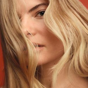 Model with blonde, wavy hair falling over eyes.