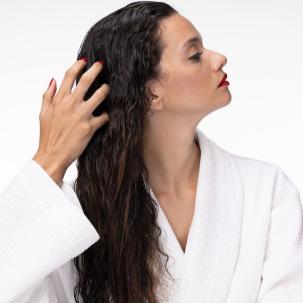 Model wearing a robe runs fingers through long, wavy, brunette hair.