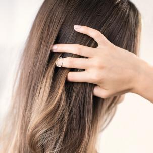 Back of woman’s head as she runs her hand through her hair.