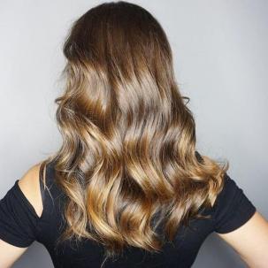 Back of woman’s head with long, wavy, glossy brunette hair, created using Wella Professionals. 
